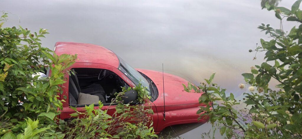 Red Dodge pickup partially submerged in water off Cherokee County Road 928 near Mud Creek
