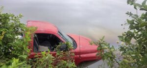 Red Dodge pickup partially submerged in water off Cherokee County Road 928 near Mud Creek