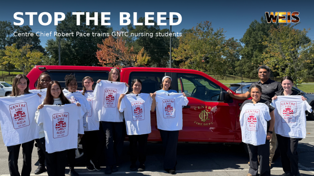 Centre Fire Chief Robert Pace and GNTC nursing students holding Centre Fire Rescue shirts beside his red truck.