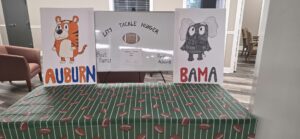 Union State Bank food drive header showing the Cedar Bluff office’s hand-drawn Alabama and Auburn display and a football tablecloth.