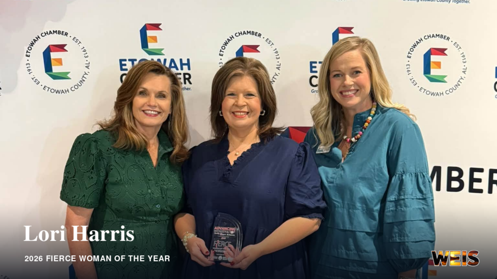 Lori Harris, center, holds her Fierce Woman of the Year award with two women in front of an Etowah Chamber backdrop.