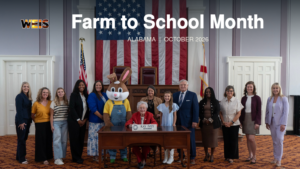 Governor Kay Ivey poses with a group in the supplied Farm to School Month photo, with the headline and WEIS branding.