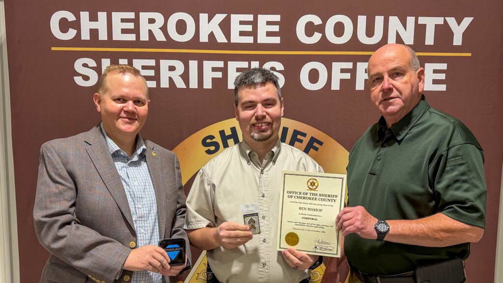 Ben Bishop corporal promotion photo showing him holding his new insignia and certificate beside Cherokee County Sheriff's Office officials.