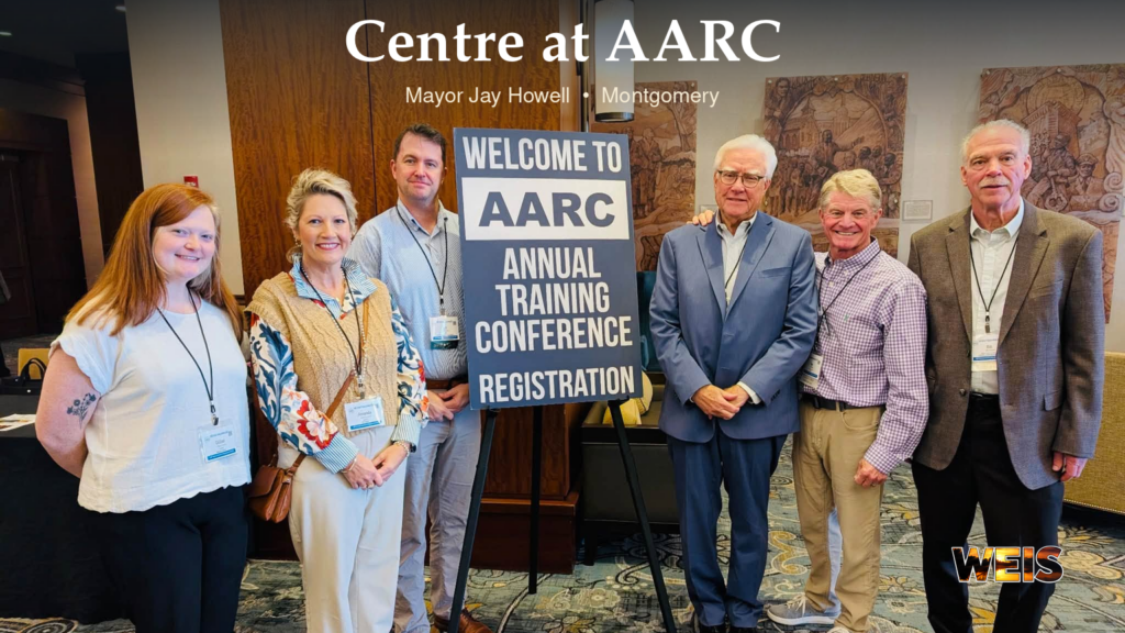 Centre Mayor Jay Howell conference header showing attendees beside the AARC registration sign in Montgomery, with WEIS branding.