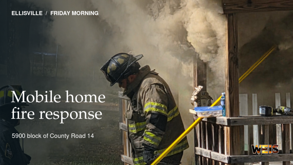 Firefighters work beside a smoke-filled mobile home during Friday morning’s fire on County Road 14 in Ellisville.