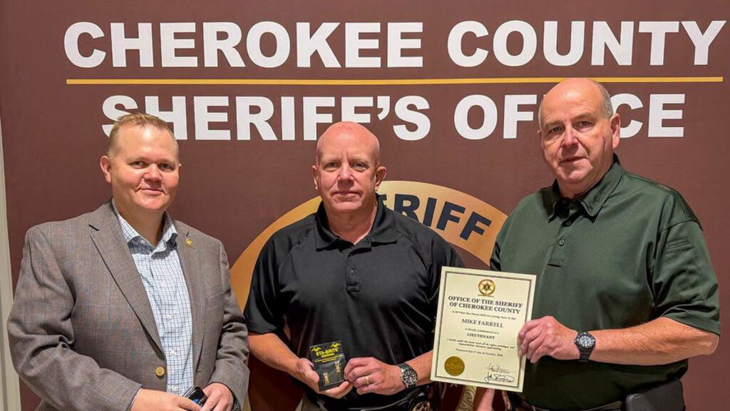 Mike Farrell promotion photo showing the new lieutenant holding his badge beside two Cherokee County Sheriff's Office officials.