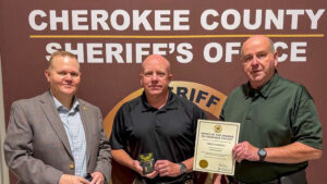 Mike Farrell promotion photo showing the new lieutenant holding his badge beside two Cherokee County Sheriff's Office officials.