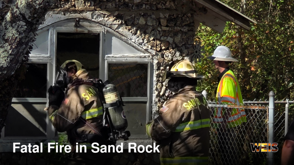 Firefighters outside a stone building at the scene of the fatal Sand Rock fire on Sand Rock Avenue.