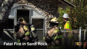 Firefighters outside a stone building at the scene of the fatal Sand Rock fire on Sand Rock Avenue.