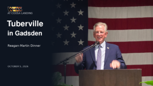 Tommy Tuberville speaking in Gadsden at the Reagan-Martin Dinner, with an American flag behind him.