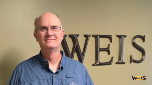 Vince Ramsey stands in front of WEIS wall lettering in a blue shirt; the WEIS logo appears at lower right.